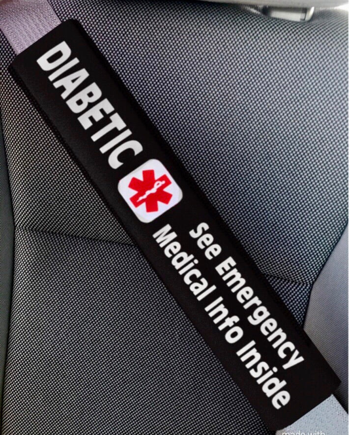 Car seat belt cover with 'Diabetic' and 'see emergency medical info inside' text on a car seat background.