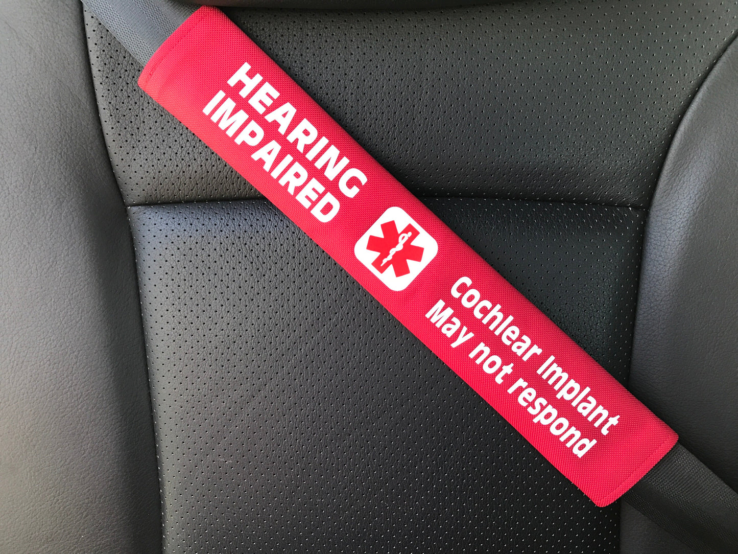 Red 'Hearing Impaired' and 'Cochlear Implant May Not Respond' strap on a car seat.